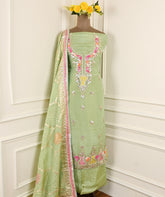 Light green traditional outfit with floral embroidery on a mannequin against a white wall.